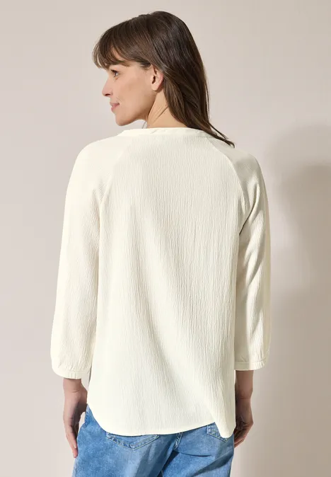 Frau mit weißem Langarmshirt und Jeans von hinten zu sehen.